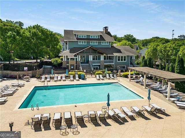 community pool featuring a patio, a pergola, and fence