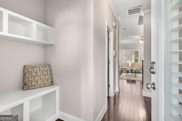hall with crown molding, visible vents, baseboards, and dark wood-style floors