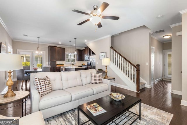living area with ceiling fan with notable chandelier, visible vents, dark wood-style flooring, stairs, and baseboards