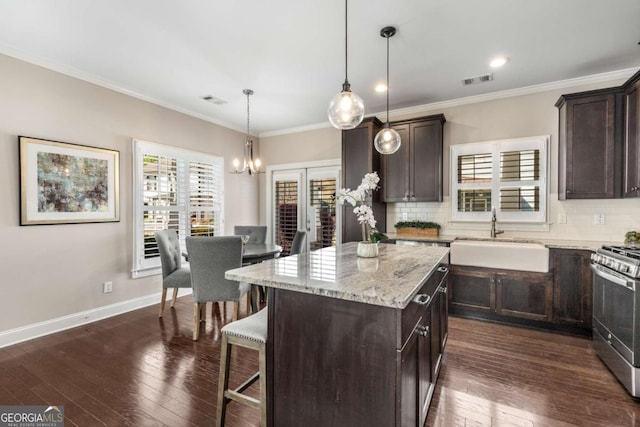 kitchen with stainless steel range with gas stovetop, a sink, a wealth of natural light, and dark brown cabinetry