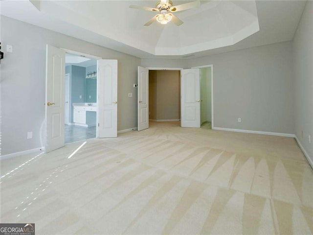 3195 Vickery Dr NE, Marietta, GA 30066 - unfurnished bedroom featuring a tray ceiling, baseboards, ensuite bath, and light carpet
