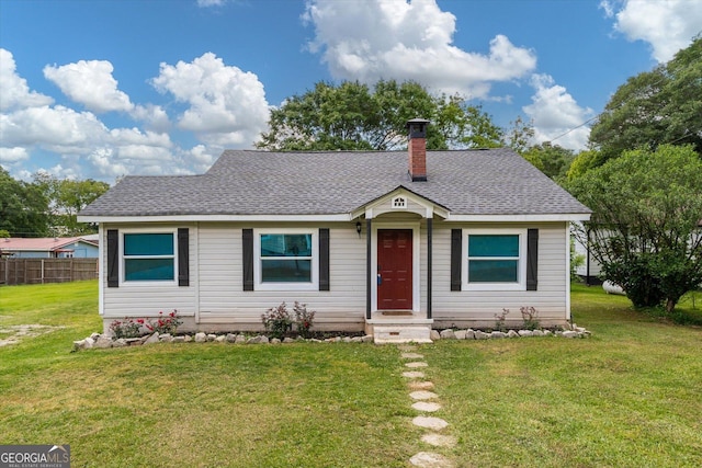 bungalow-style home featuring a chimney, a front yard, roof with shingles, and fence