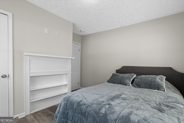 bedroom featuring a textured ceiling, wood finished floors, and baseboards