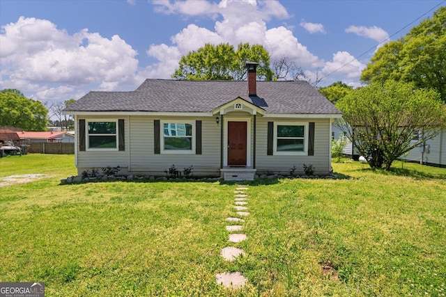 bungalow-style house featuring a chimney, roof with shingles, and a front lawn