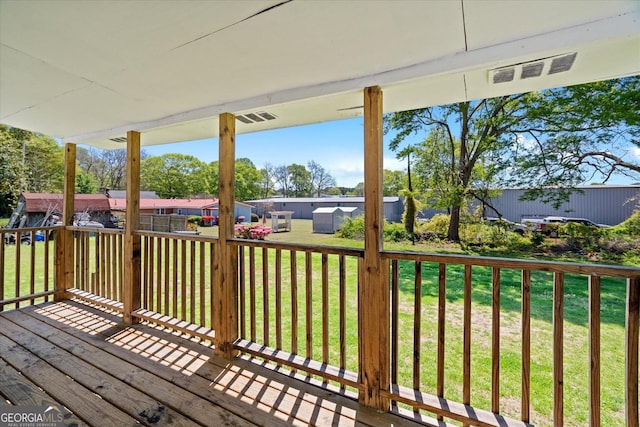 wooden deck featuring a yard, an outdoor structure, visible vents, and a storage unit