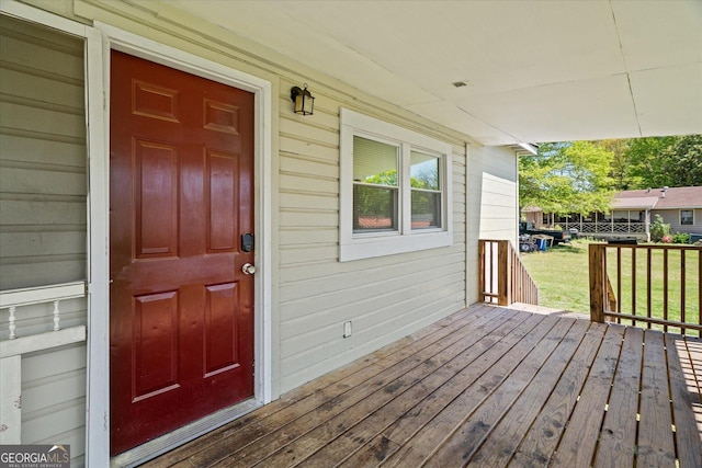 view of exterior entry featuring a porch and a lawn