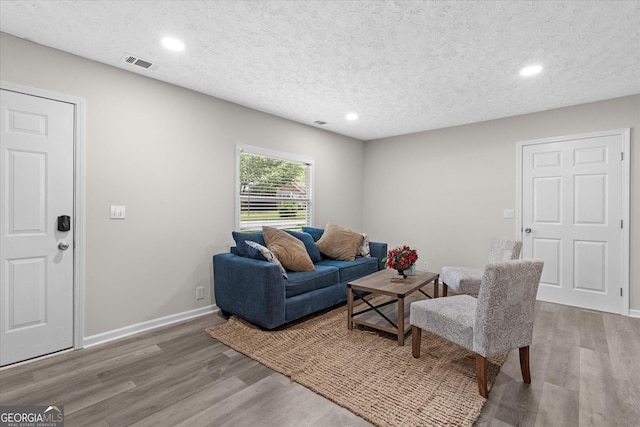 living room with visible vents, a textured ceiling, and wood finished floors