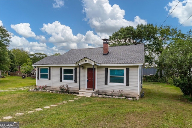 view of front of property featuring roof with shingles, a front lawn, and a chimney