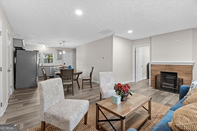 205 Mara St, Carrollton, GA 30117 - living room featuring a textured ceiling, a fireplace with flush hearth, light wood-type flooring, and recessed lighting