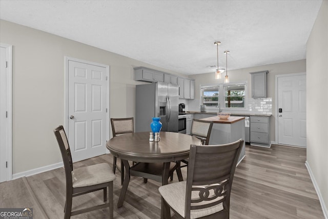 dining room featuring a textured ceiling, wood finished floors, and baseboards