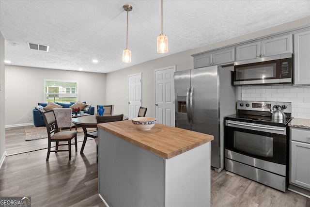 kitchen featuring butcher block countertops, light wood-type flooring, visible vents, gray cabinetry, and appliances with stainless steel finishes