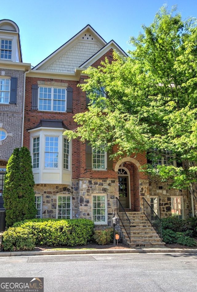 townhome / multi-family property featuring brick siding, central air condition unit, and stone siding
