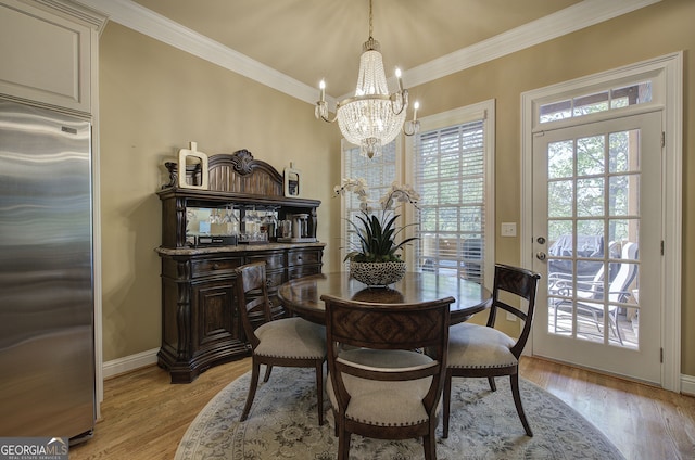 dining room with a notable chandelier, crown molding, and light wood-style flooring