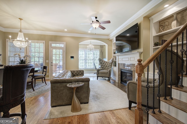 living area featuring crown molding, wood finished floors, and ceiling fan with notable chandelier