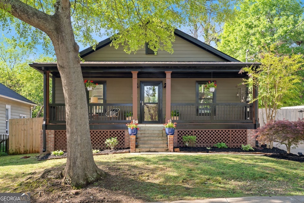 bungalow featuring a front yard, a porch, and fence