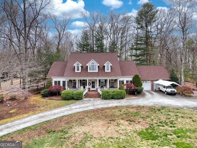 cape cod-style house with curved driveway, covered porch, a garage, and a front yard