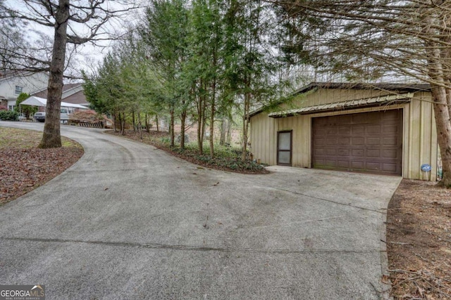 view of home's exterior with driveway, a garage, and an outbuilding