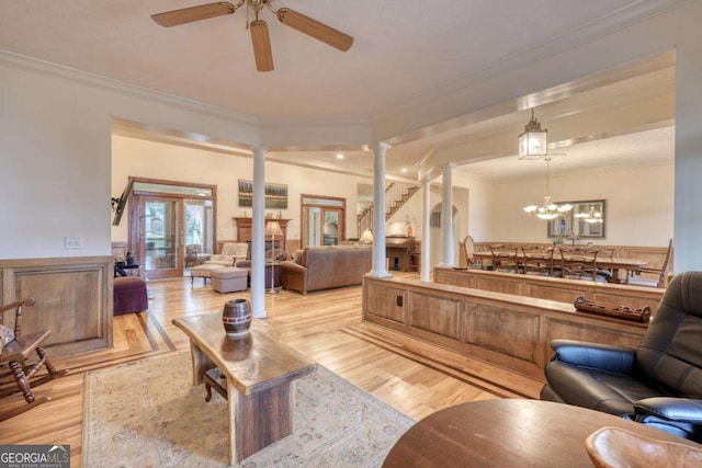 living room with ornate columns, crown molding, ceiling fan, light wood-style floors, and a chandelier
