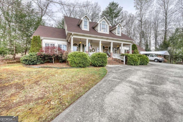 cape cod house featuring covered porch, driveway, and a front lawn