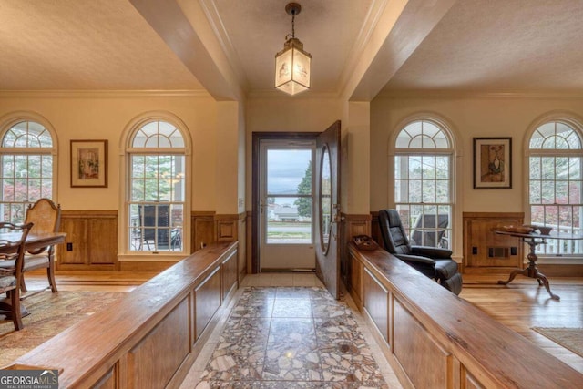 entryway featuring a wainscoted wall and crown molding