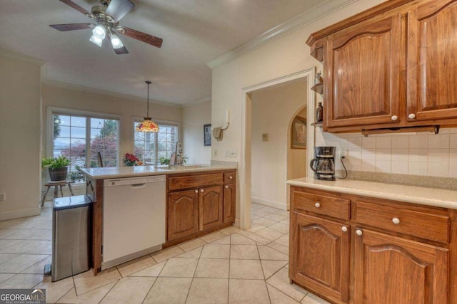 kitchen featuring dishwasher, a sink, brown cabinetry, light countertops, and crown molding