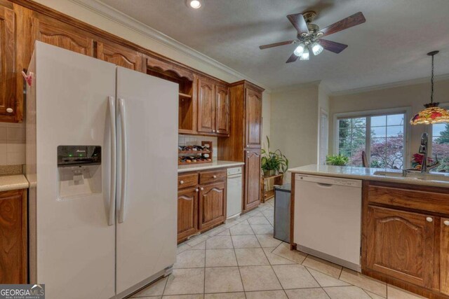 kitchen featuring white appliances, a sink, decorative backsplash, light countertops, and ornamental molding
