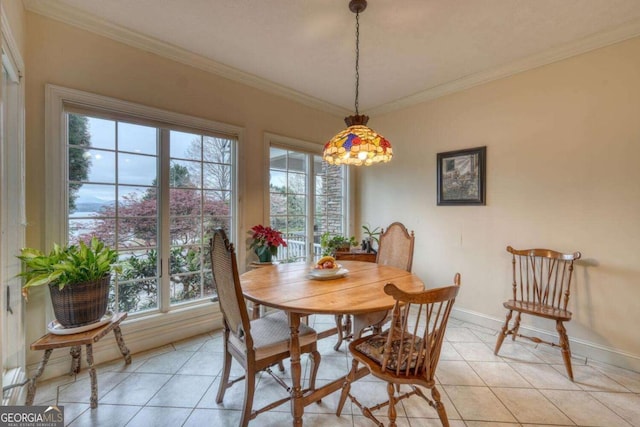 dining space with light tile patterned floors, ornamental molding, and baseboards