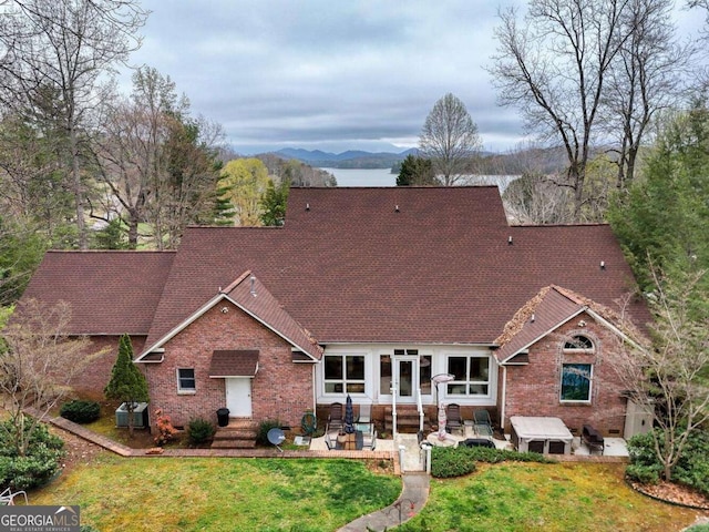 view of front of property with a mountain view, brick siding, a front yard, and a patio