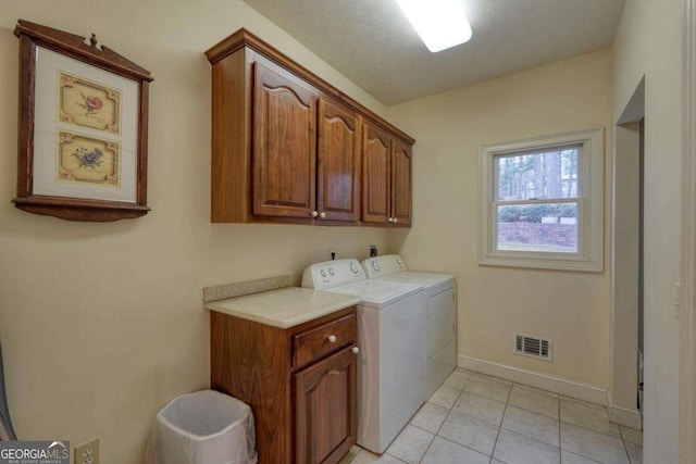laundry area with cabinet space, separate washer and dryer, baseboards, and light tile patterned floors