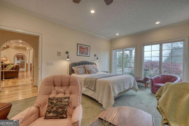 bedroom featuring arched walkways, ornamental molding, light carpet, recessed lighting, and a textured ceiling