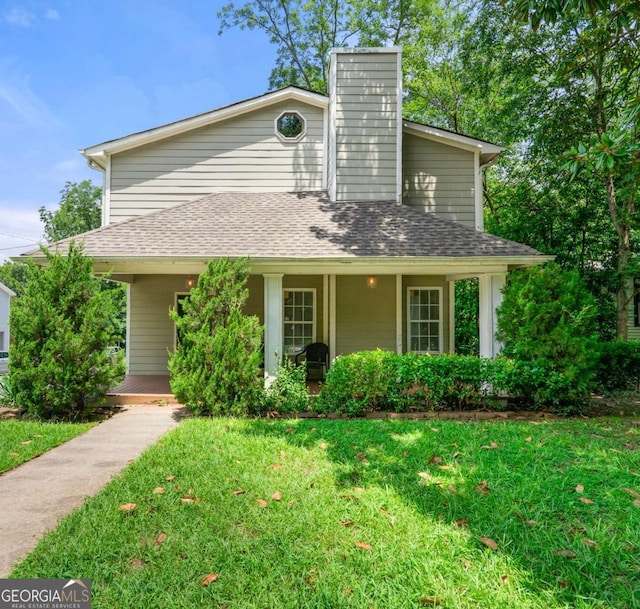 view of front facade featuring a porch, a shingled roof, a front lawn, and a chimney