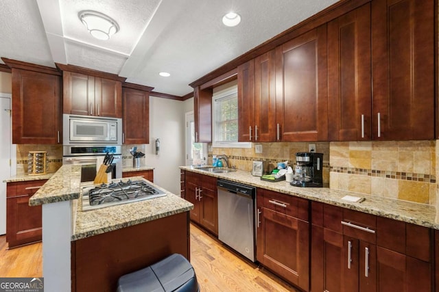 kitchen featuring stainless steel appliances, a sink, light wood-type flooring, ornamental molding, and tasteful backsplash