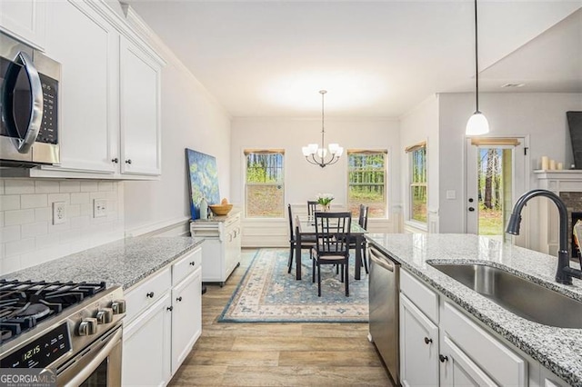 1195 Awenasa Dr, Villa Rica, GA 30180 - kitchen with a notable chandelier, appliances with stainless steel finishes, a sink, light wood-style flooring, and white cabinetry