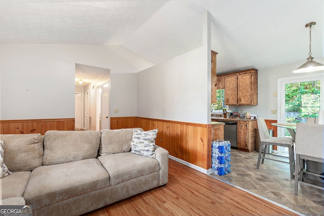 living room with wood walls, vaulted ceiling, and a wainscoted wall