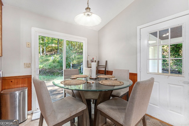dining room featuring lofted ceiling and a wainscoted wall