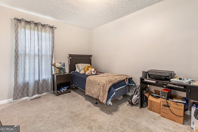 bedroom with visible vents, carpet flooring, and a textured ceiling