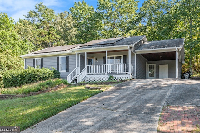 single story home featuring a front yard, roof mounted solar panels, a carport, covered porch, and concrete driveway