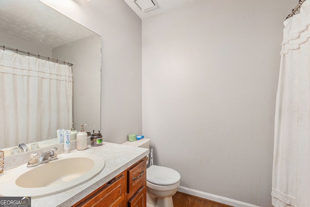 bathroom featuring toilet, wood finished floors, vanity, and baseboards