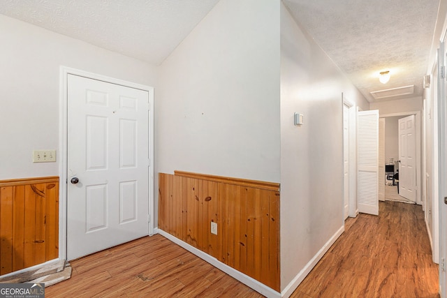 corridor with wood finished floors and a textured ceiling