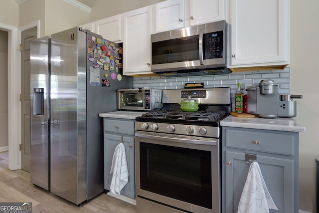 101 Javay Ct, Villa Rica, GA 30180 - kitchen featuring appliances with stainless steel finishes, light countertops, backsplash, white cabinets, and ornamental molding