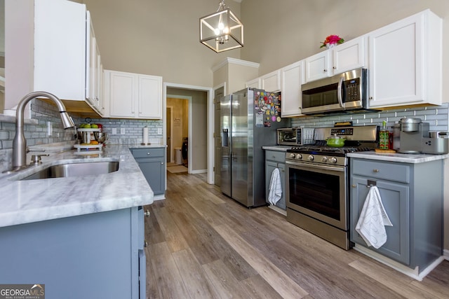 101 Javay Ct, Villa Rica, GA 30180 - kitchen with appliances with stainless steel finishes, tasteful backsplash, white cabinets, a towering ceiling, and light wood-type flooring