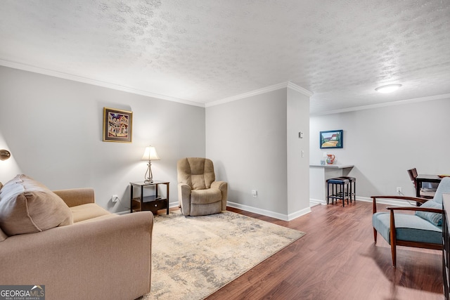 living room featuring baseboards, a textured ceiling, crown molding, and wood finished floors