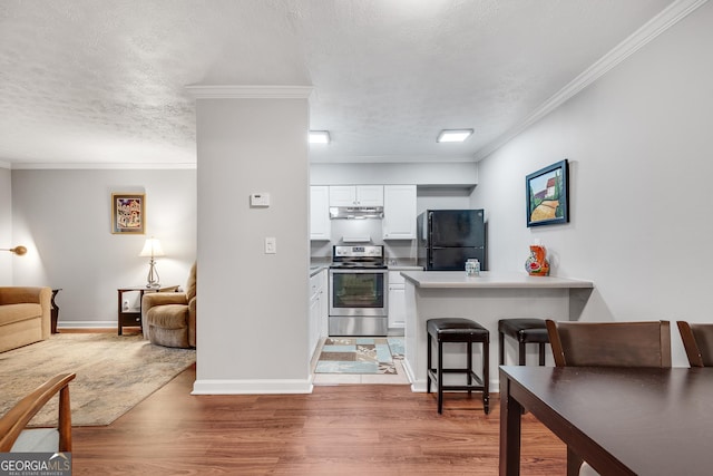 kitchen featuring freestanding refrigerator, stainless steel electric stove, a peninsula, crown molding, and white cabinetry