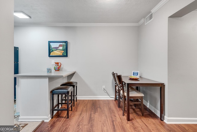 dining area featuring crown molding, wood finished floors, baseboards, and visible vents