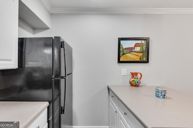 kitchen featuring freestanding refrigerator, white cabinetry, ornamental molding, light countertops, and baseboards