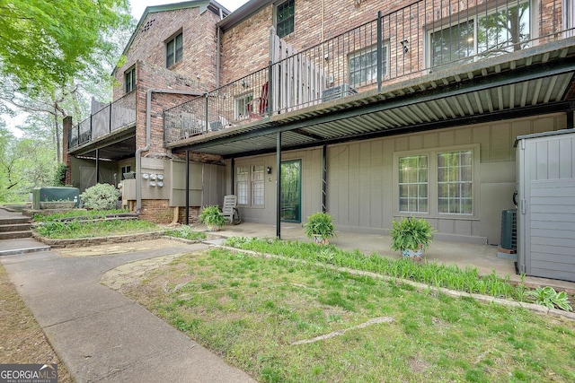exterior space with brick siding, cooling unit, and a patio