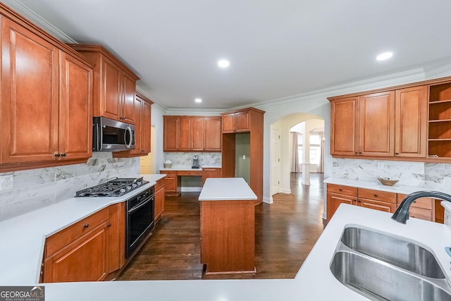 kitchen with arched walkways, wall oven, gas cooktop, stainless steel microwave, and a sink