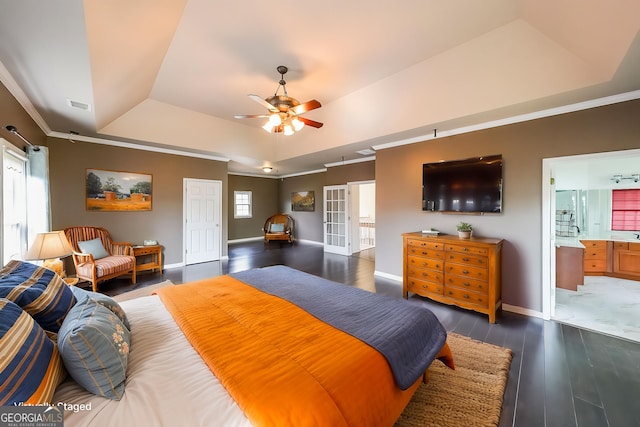 bedroom featuring baseboards, ornamental molding, visible vents, a tray ceiling, and wood finished floors