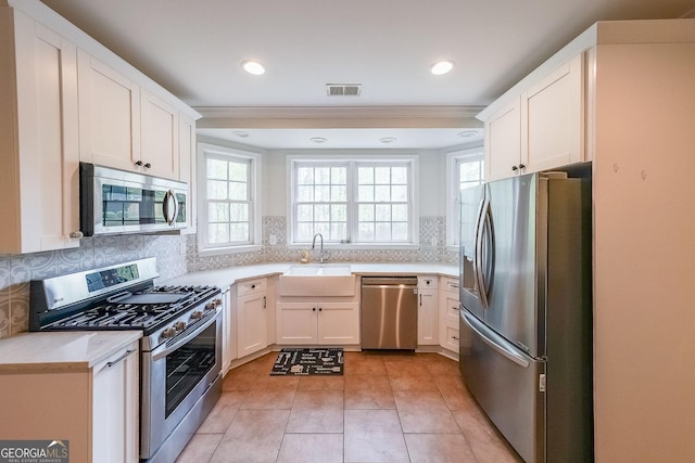 kitchen with tasteful backsplash, light countertops, visible vents, appliances with stainless steel finishes, and a sink