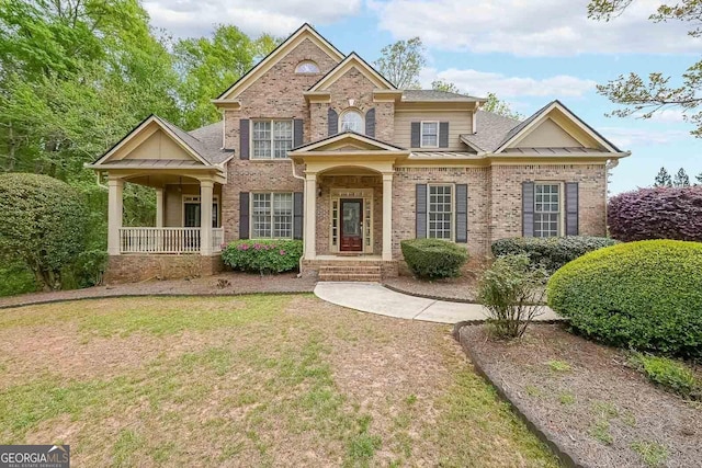 craftsman-style home with a standing seam roof, metal roof, a front lawn, brick siding, and a shingled roof